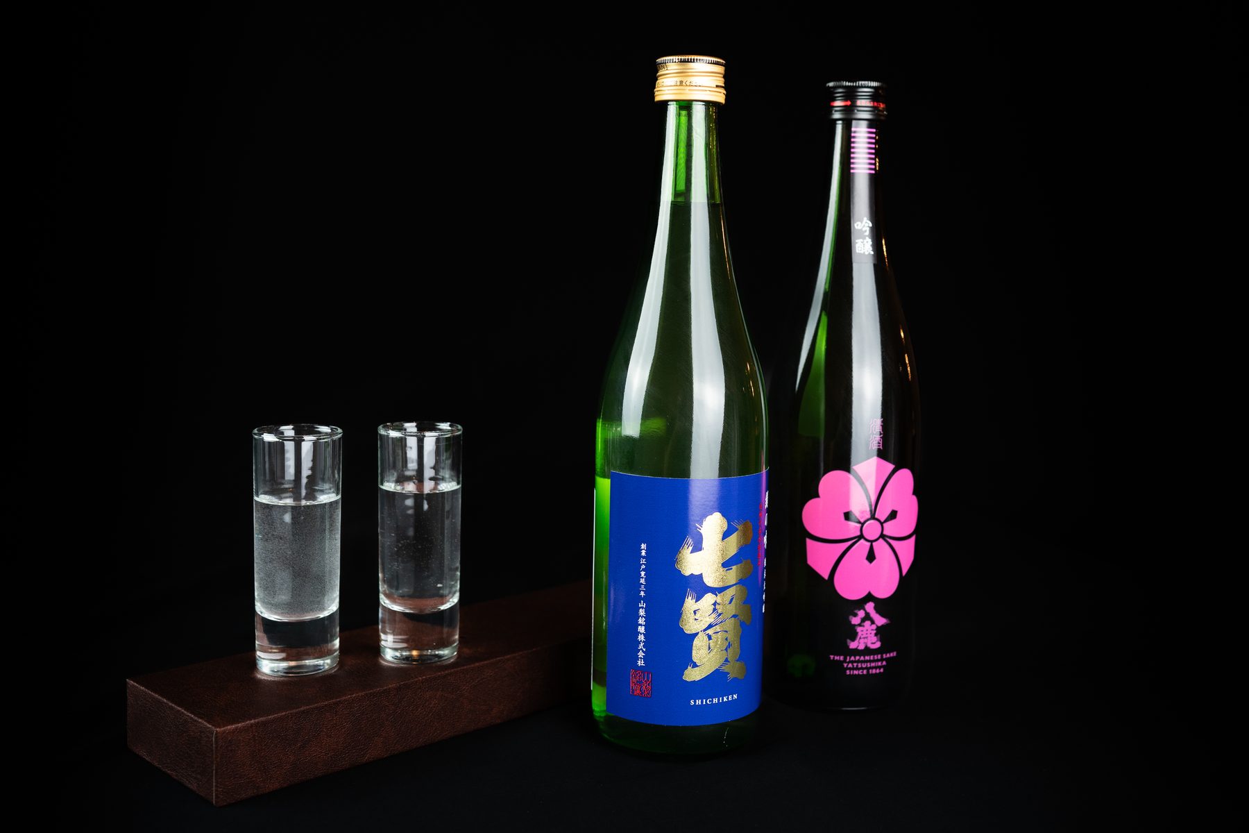 Botellas de sake premium con vasitos sobre madera