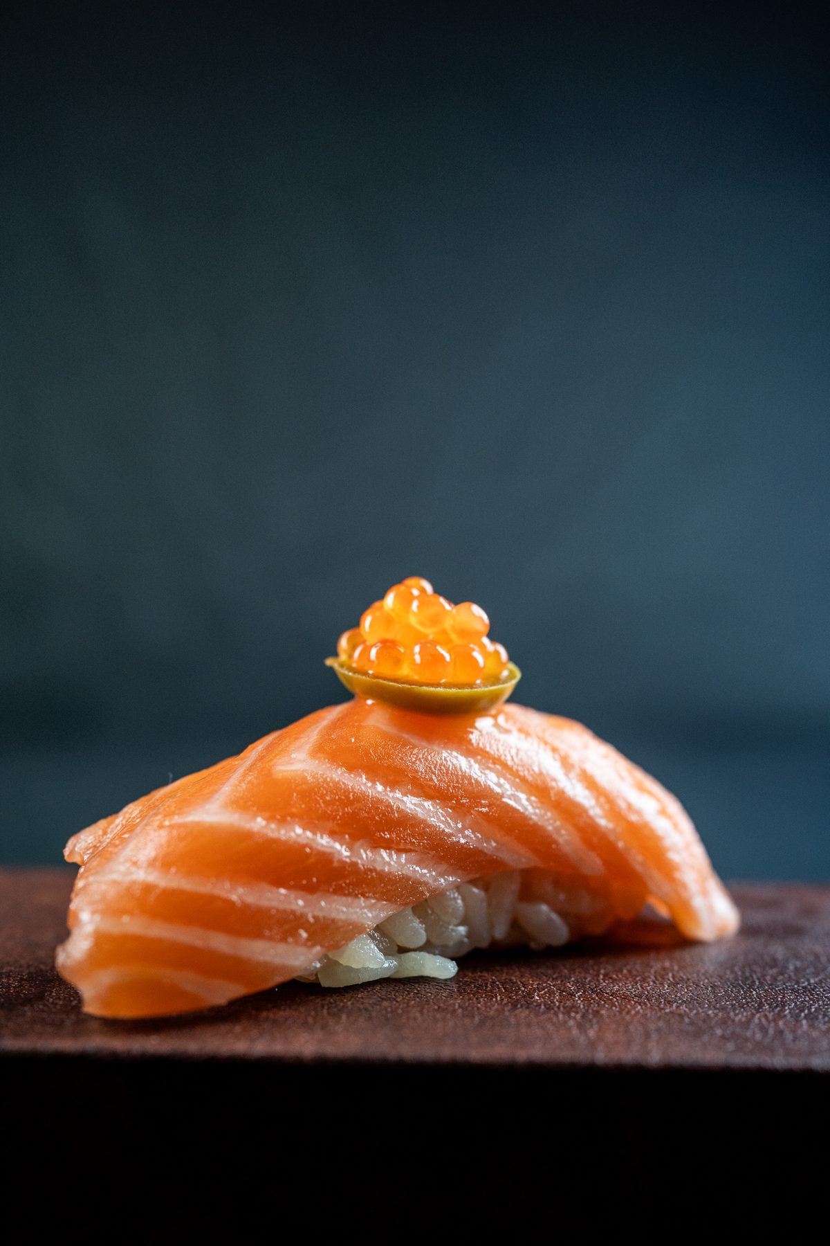 Nigiri de salmón con huevas de salmón sobre tabla de madera